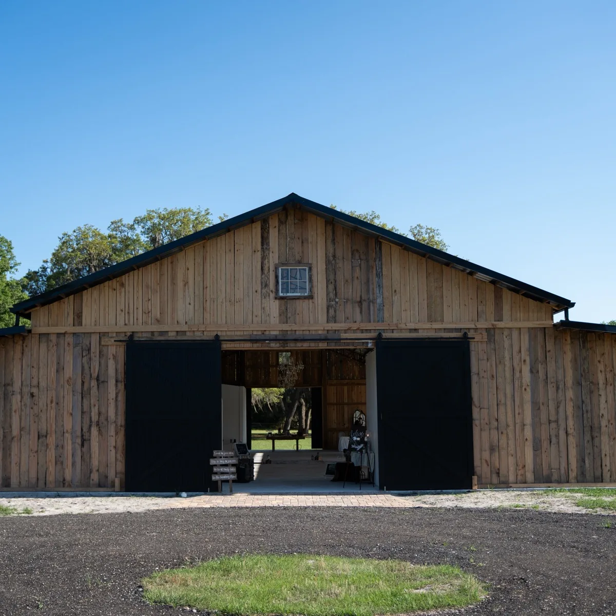 The barn's front elevation, weathered vertical wood siding with black sliding doors open to the central breezeway